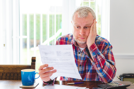 Worried man checking energy bills at home